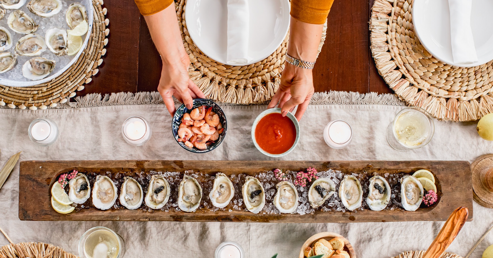 Image of the setup of an oyster tasting event, including oysters on ice, shrimp, sauce, and olive oil.